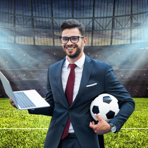 ein Young Professional steht strahlend im Stadion, in der rechten Hand hält er ein Notebook, im linken Arm einen Fußball; Symbolbild für den Bewerbertag in Riesa