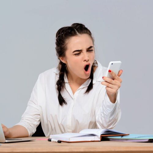 Junge Büroangestellte spricht wütend in ihr Smartphone